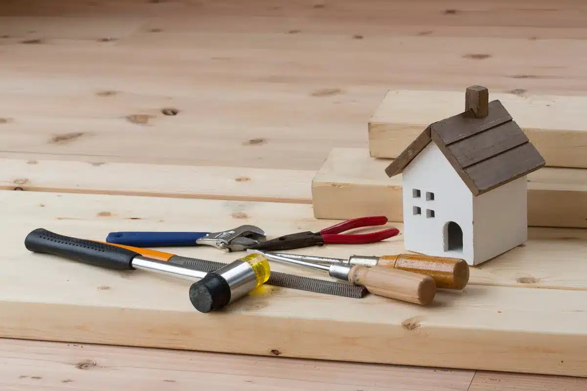 Outils et matériaux de rénovation disposés sur un plan de travail en bois, illustrant les équipements nécessaires pour rénover sa maison efficacement.